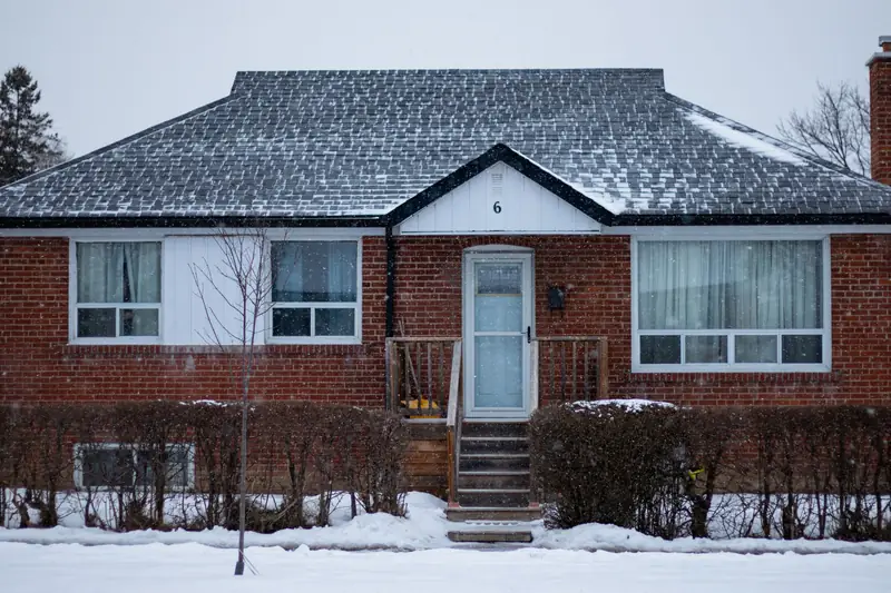 A brick house on a residential street after a snowfall, in daylight