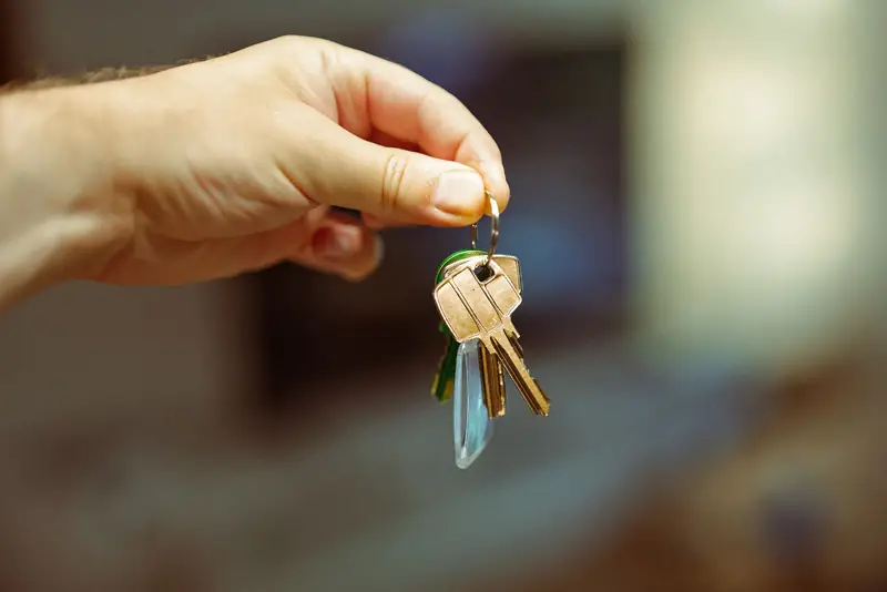 A hand holding up a set of house keys