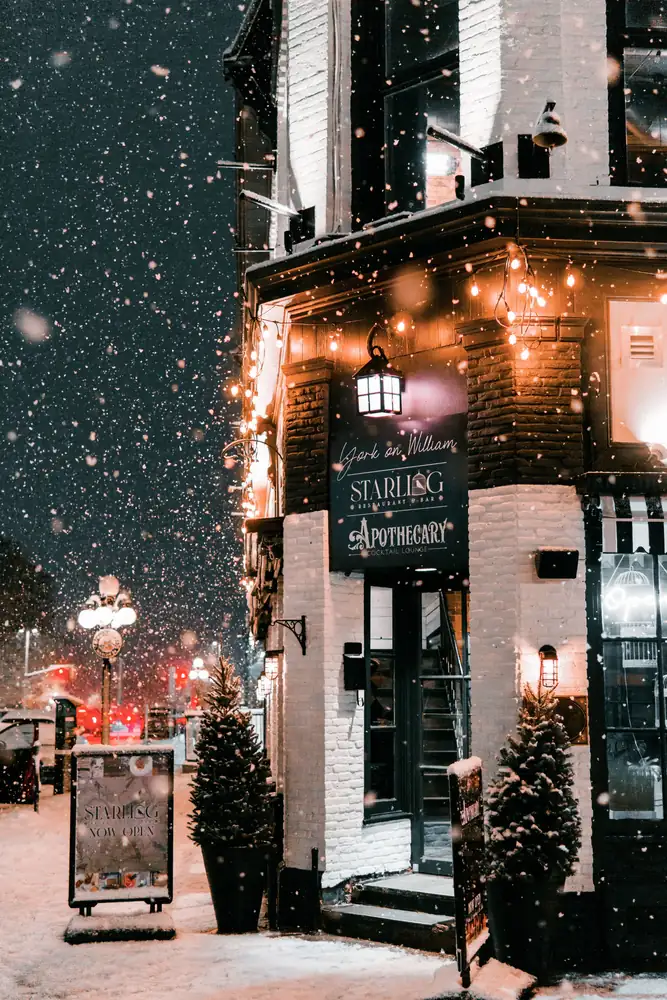 A lit shop entrance during a snowstorm at night